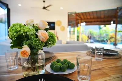 a table with a vase of roses and a plate of limes at Villa Zenta in Canggu