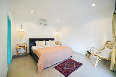 a bedroom with a bed and a chair at Villa Zenta in Canggu