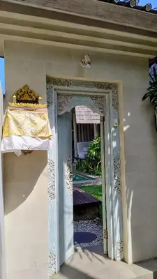 an open door to a house with a yellow curtain at Villa Made West in Seminyak