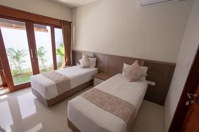 a bedroom with two beds and a window at Juada Garden in Seminyak