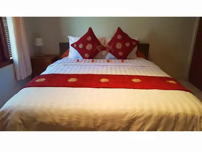 a bed with red and white sheets and red pillows at Juada Garden in Seminyak
