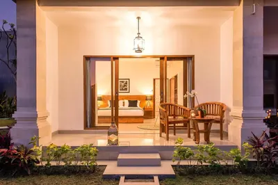 a room with a bedroom with a bed and a table at Puri Uma Ratu by RPM in Seminyak