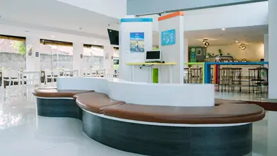 a waiting room with a bench and tables and chairs at POP! Hotel Kuta Beach in Kuta