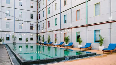a hotel pool with blue chairs and a building at POP! Hotel Kuta Beach in Kuta