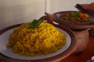 a plate of yellow rice on a table with other dishes at Sarinande Hotel in Seminyak