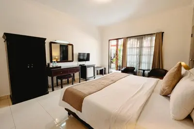 a bedroom with a bed and a desk and a television at Sarinande Hotel in Seminyak