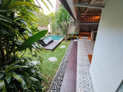 a backyard with a swimming pool and some plants at Villa Made East in Seminyak