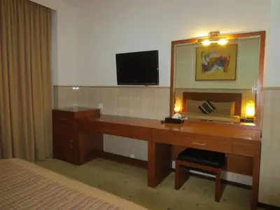 a bedroom with a desk with a mirror and a television at Bali Paradise City Hotel in Denpasar