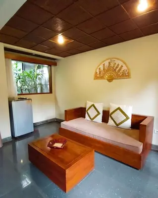 a room with a bed and a table and a refrigerator at Nyuh Bali Villas in Seminyak