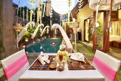 a table and chairs with a table and a swimming pool at Nyuh Bali Villas in Seminyak