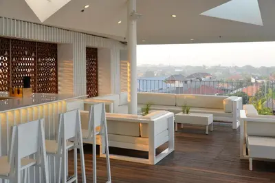 a restaurant with white tables and chairs and a balcony at IZE Seminyak by LifestyleRetreats in Seminyak