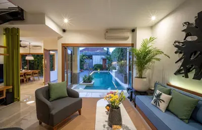 a living room with a couch and a chair and a pool at Villa Artisane in Seminyak
