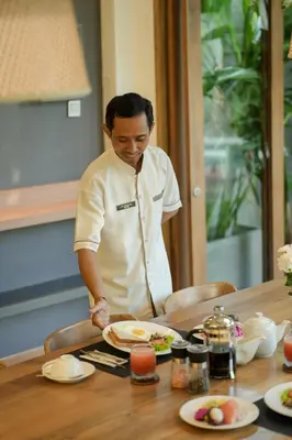 a man preparing a plate of food on a table at Villa Artisane in Seminyak