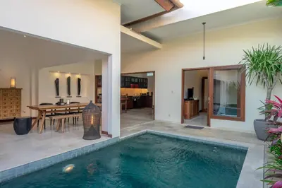 a swimming pool in a villa with a dining area and a house at Amandaru Villa by RPM in Legian