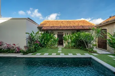 a villa with a swimming pool in front of a house at Amandaru Villa by RPM in Legian