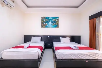 a bedroom with two beds and a painting on the wall at Samudra Homestay in Kuta