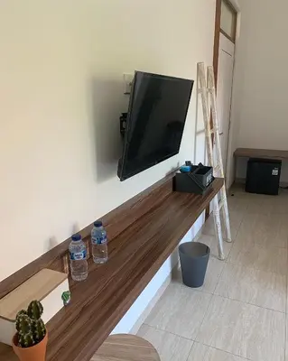 a flat screen tv on a wall in a living room at Beach Hut Hostel in Kuta