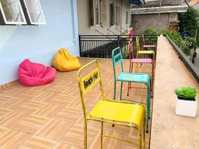 a row of colorful chairs and bean bags on a porch at Beach Hut Hostel in Kuta