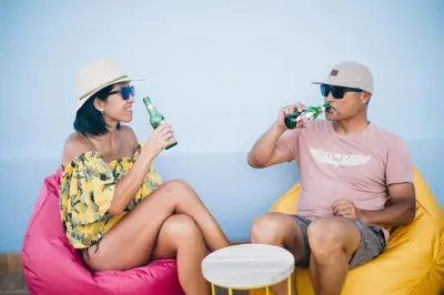 a man and woman sitting on a couch drinking beer at Beach Hut Hostel in Kuta