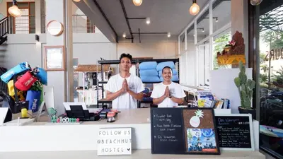 two men are standing behind a counter in a store at Beach Hut Hostel in Kuta