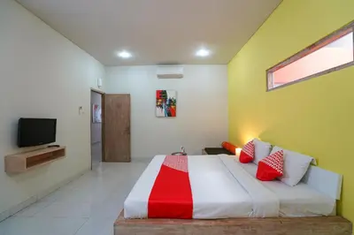 a bedroom with a large bed with red and white pillows at Cityzen Renon Hotel in Denpasar