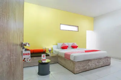 a bedroom with a bed and a yellow wall at Cityzen Renon Hotel in Denpasar