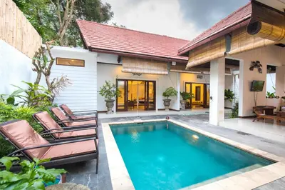 a villa with a swimming pool and a house at Villa Kamboja Five in Seminyak