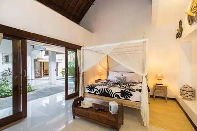 a bedroom with a bed with a mosquito net at Villa Kamboja Five in Seminyak