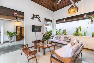 a living room with a couch and chairs and a tv at Villa Kamboja Five in Seminyak