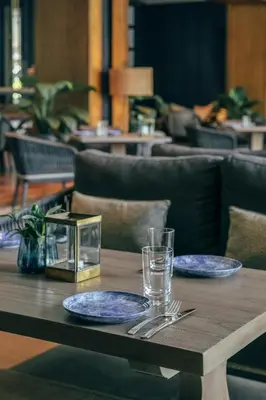 a wooden table with two plates and glasses on it at Kanvaz Village Resort Seminyak in Seminyak