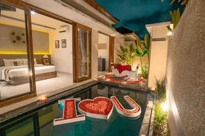 a hotel room with a bed and a pool with red heart seats at The Sakaye Villas & Spa by Kanaya Hospitality in Legian