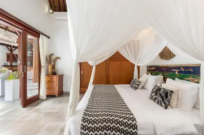 a bedroom with a white bed with white drapes at Villa Cinta Umalas in Canggu