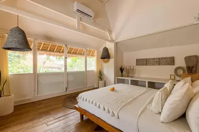 a bedroom with a large bed and a window at Oma Villa - A tropical sanctuary of Seminyak in Seminyak