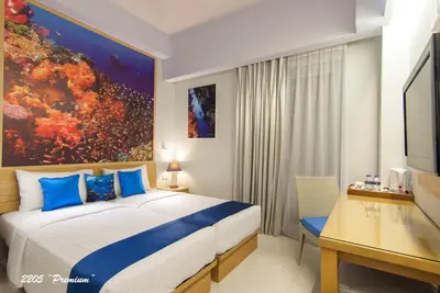 a bedroom with a bed and a desk with a computer at Rhadana Hotel in Kuta