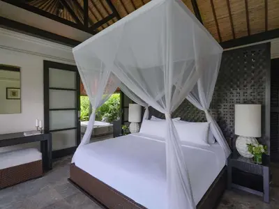 a bedroom with a white bed with a canopy at Peppers Seminyak in Seminyak