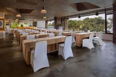 a restaurant with long tables and white chairs at Truntum Kuta Bali in Kuta