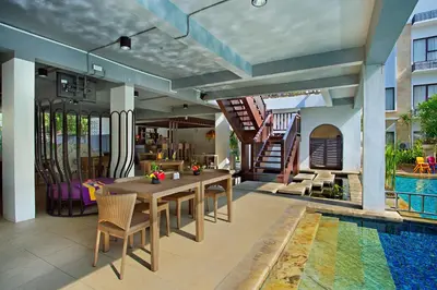 a dining room with a table and a swimming pool at Truntum Kuta Bali in Kuta