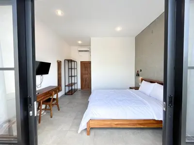 a bedroom with a bed and a desk and a television at Adi surya guest house in Seminyak