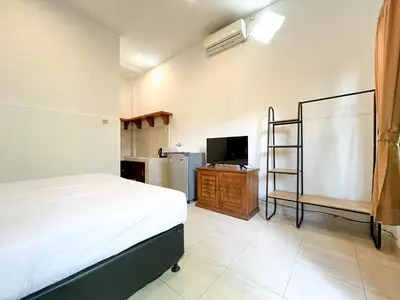 a bedroom with a bed and a tv and a kitchen at Adi surya guest house in Seminyak