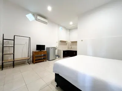 a bedroom with a white bed and a television at Adi surya guest house in Seminyak