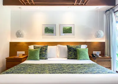 a bedroom with a large bed with green pillows at Legian Beach Hotel in Legian