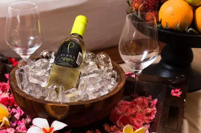a bottle of wine in a bowl of ice with two wine glasses at Hotel Vila Lumbung in Seminyak