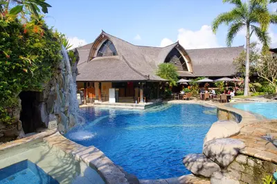 a swimming pool in a resort with a building at Hotel Vila Lumbung in Seminyak