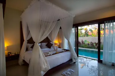 a bedroom with a canopy bed and a swimming pool at The Awan Villas Seminyak in Seminyak