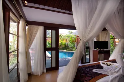 a bedroom with a bed and a view of a pool at The Awan Villas Seminyak in Seminyak