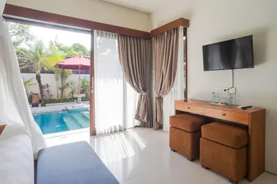 a bedroom with a bed and a television and a pool at The Awan Villas Seminyak in Seminyak
