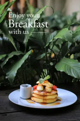 a plate with a stack of pancakes with a cup of coffee at Grandmas Plus Hotel Legian in Legian