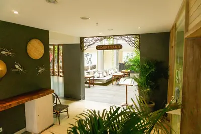 a lobby with a restaurant with tables and chairs at Grandmas Plus Hotel Legian in Legian