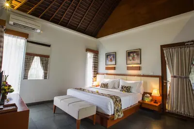 a bedroom with a large white bed and a chair at The Astari Villa and Residence in Jimbaran