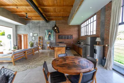 a living room with a wooden table and a kitchen at Villa Maje by Alfred in Bali in Seminyak